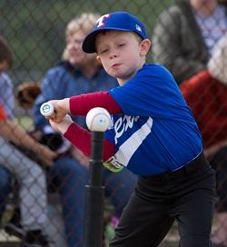 Child swinging bat at a ball on a Tee